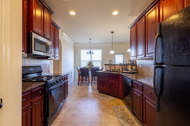 kitchen with dark stone counters, black appliances, sink, tasteful backsplash, and decorative light fixtures