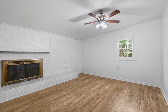 unfurnished living room with ceiling fan, wood-type flooring, and a brick fireplace