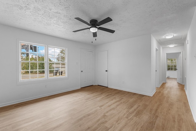 spare room with a textured ceiling, light wood-type flooring, and ceiling fan