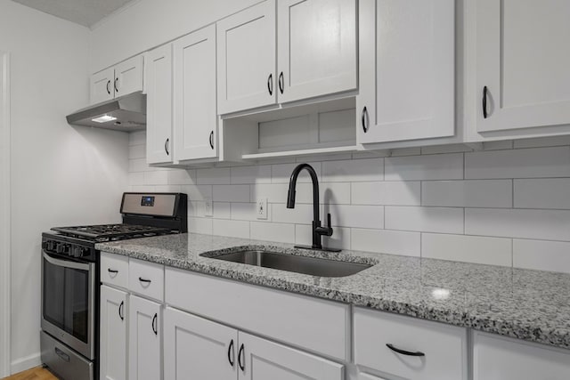 kitchen featuring gas range, backsplash, white cabinetry, and sink