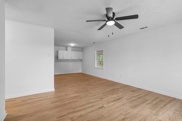 empty room with a textured ceiling, light wood-type flooring, and ceiling fan