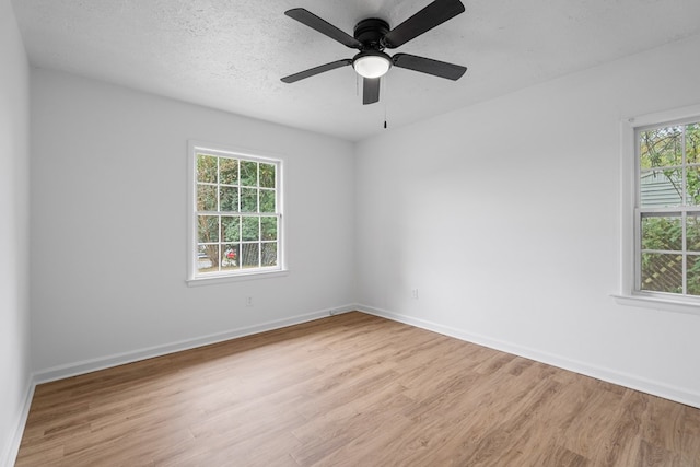 empty room featuring a textured ceiling, light hardwood / wood-style floors, a wealth of natural light, and ceiling fan