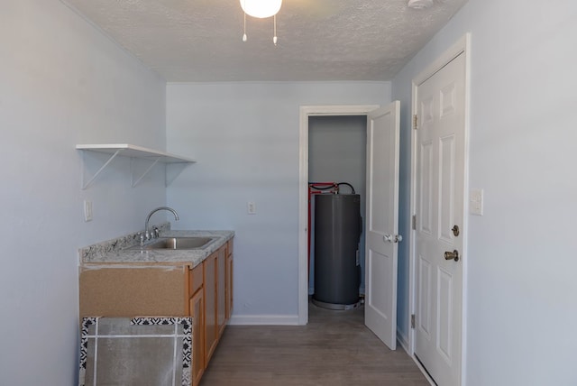 kitchen with a textured ceiling, water heater, dark wood-type flooring, and sink