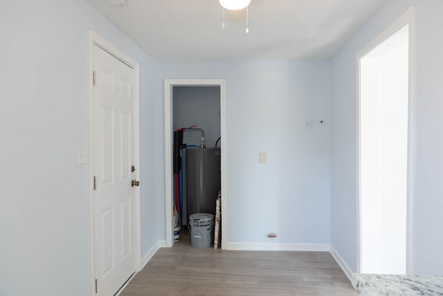 corridor featuring water heater, light hardwood / wood-style flooring, and a textured ceiling