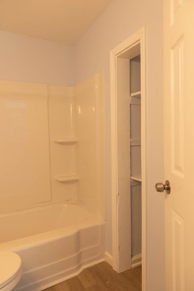 bathroom with hardwood / wood-style floors, toilet, and shower / bathtub combination