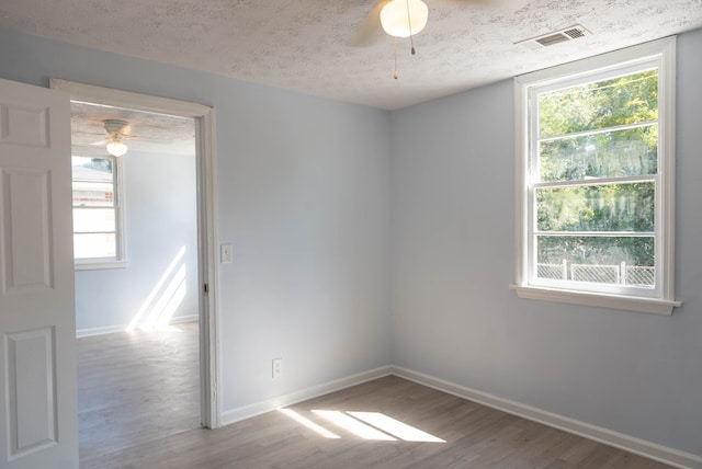 spare room with plenty of natural light, a textured ceiling, and light wood-type flooring