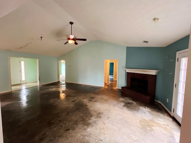 unfurnished living room featuring lofted ceiling, a brick fireplace, concrete flooring, and a healthy amount of sunlight