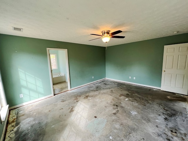 unfurnished bedroom with ceiling fan, ensuite bathroom, concrete floors, and a textured ceiling