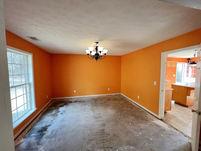 unfurnished dining area featuring an inviting chandelier, a healthy amount of sunlight, and a textured ceiling