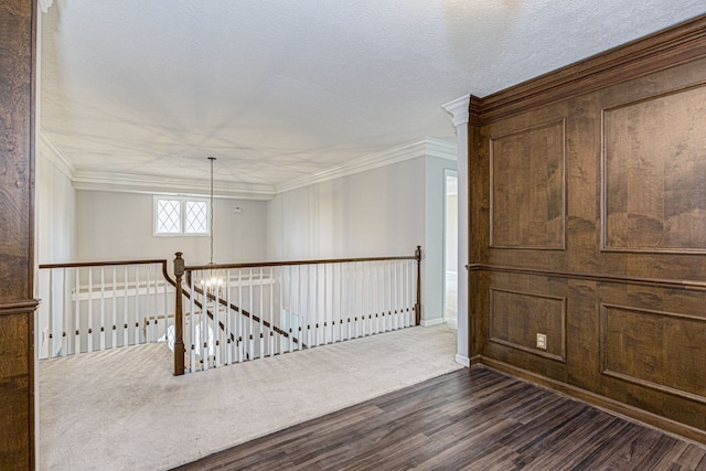 interior space featuring an upstairs landing, a textured ceiling, dark wood finished floors, an inviting chandelier, and crown molding