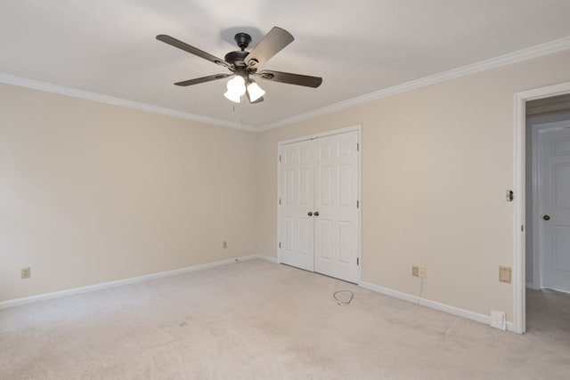 unfurnished bedroom featuring baseboards, ornamental molding, light carpet, a closet, and a ceiling fan