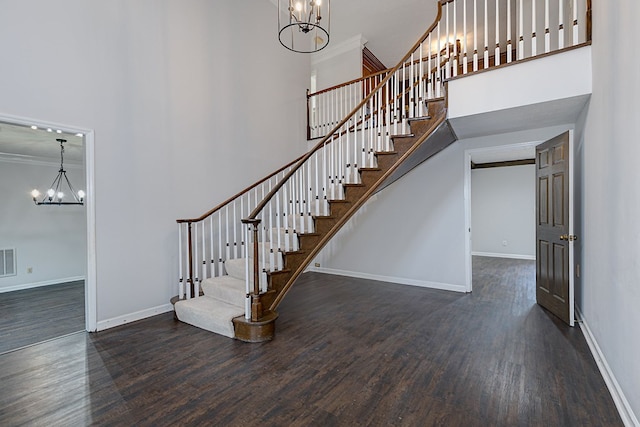 stairway featuring wood finished floors, a high ceiling, and a chandelier