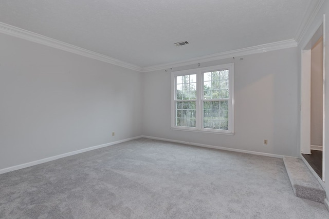 carpeted spare room featuring visible vents, baseboards, a textured ceiling, and ornamental molding