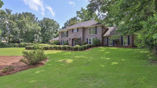 colonial home featuring a front yard and brick siding