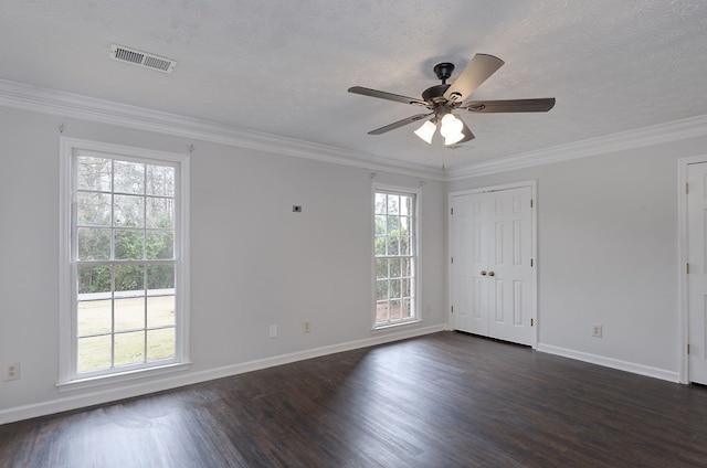 spare room featuring dark wood finished floors, crown molding, visible vents, and ceiling fan