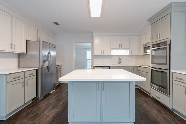 kitchen with visible vents, a sink, tasteful backsplash, a center island, and appliances with stainless steel finishes