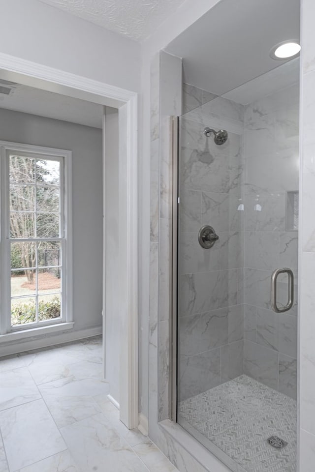 bathroom with baseboards, marble finish floor, and a stall shower