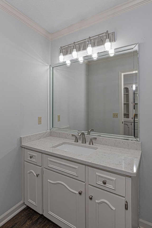 bathroom with wood finished floors, vanity, baseboards, and ornamental molding