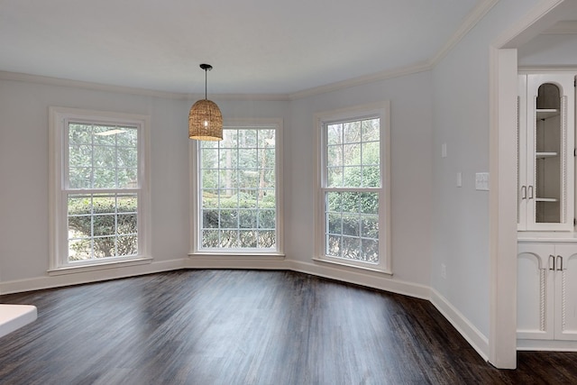 unfurnished dining area featuring dark wood finished floors, a healthy amount of sunlight, crown molding, and baseboards