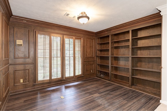 spare room featuring visible vents, crown molding, built in features, dark wood-style floors, and a decorative wall