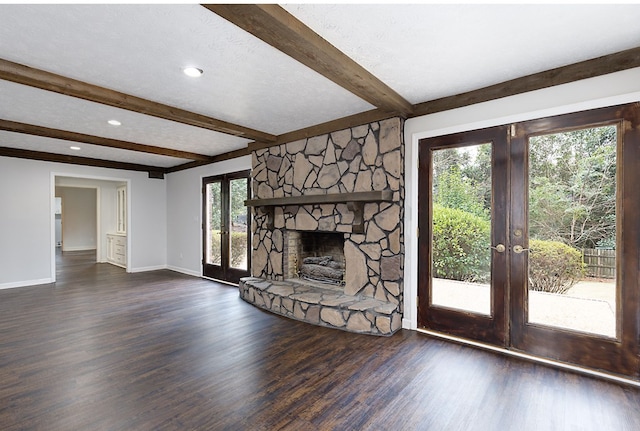 unfurnished living room with beamed ceiling, wood finished floors, french doors, a fireplace, and baseboards