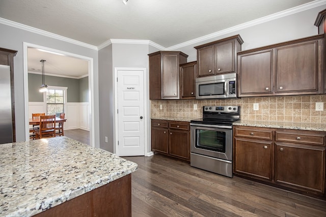 kitchen with hanging light fixtures, dark hardwood / wood-style flooring, dark brown cabinetry, light stone countertops, and appliances with stainless steel finishes