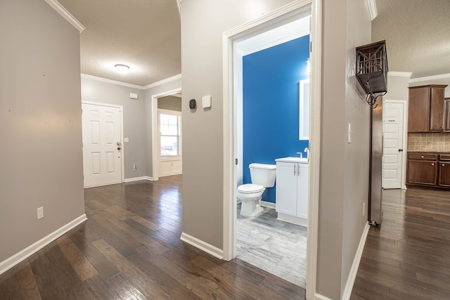 hallway with crown molding, dark hardwood / wood-style floors, and a textured ceiling