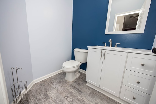 bathroom with toilet, vanity, and wood-type flooring