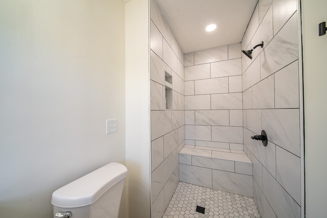 bathroom with toilet, a textured ceiling, and tiled shower