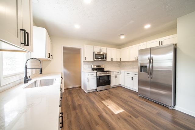 kitchen featuring white cabinetry, sink, stainless steel appliances, dark hardwood / wood-style floors, and a textured ceiling