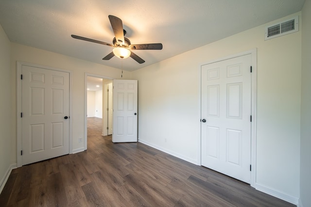 unfurnished bedroom with a textured ceiling, ceiling fan, and dark wood-type flooring