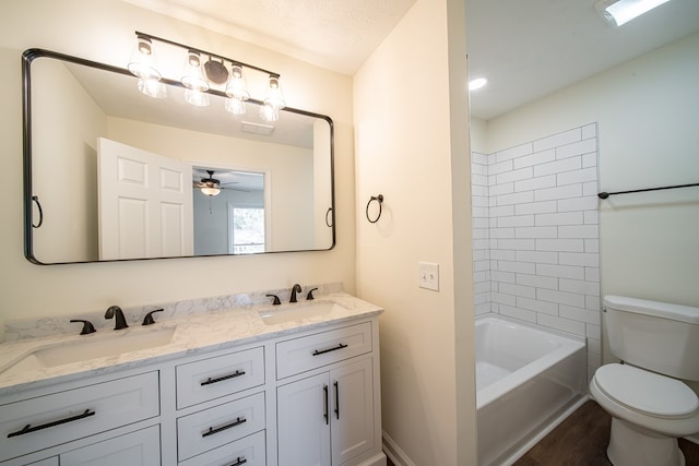 full bathroom with vanity, a textured ceiling, ceiling fan, toilet, and tiled shower / bath