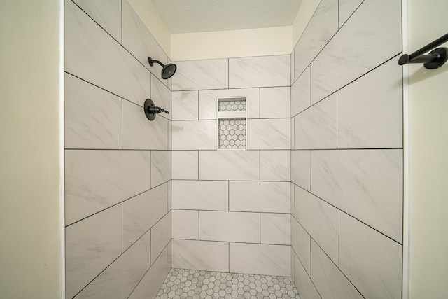 bathroom featuring a tile shower and a textured ceiling