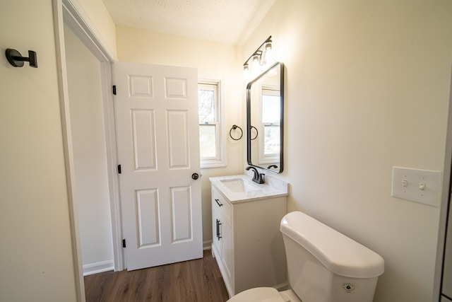 bathroom with vanity, toilet, wood-type flooring, and a textured ceiling