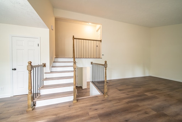 stairway with wood-type flooring and a textured ceiling