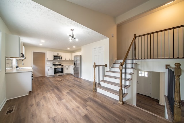 unfurnished living room with sink, an inviting chandelier, a textured ceiling, and hardwood / wood-style flooring