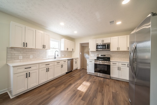 kitchen with white cabinetry, sink, stainless steel appliances, dark hardwood / wood-style floors, and a textured ceiling