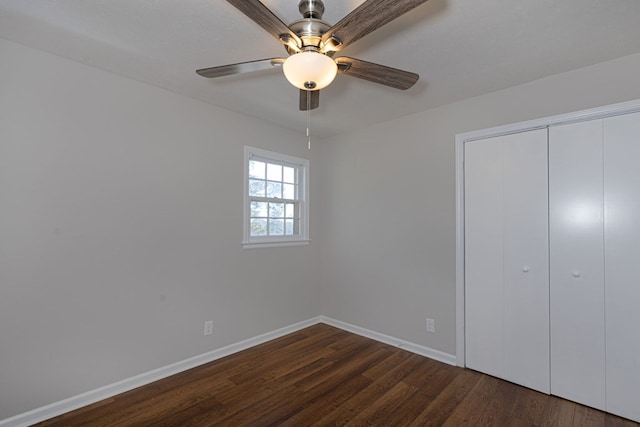 unfurnished bedroom featuring dark wood-type flooring, a closet, ceiling fan, and baseboards