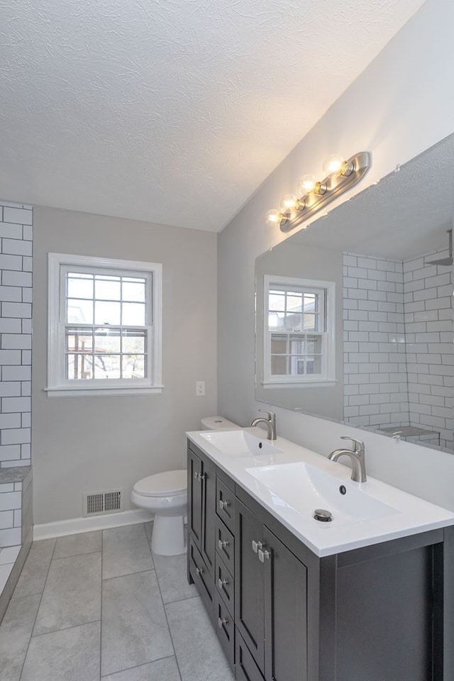 full bathroom with visible vents, a sink, a textured ceiling, and double vanity