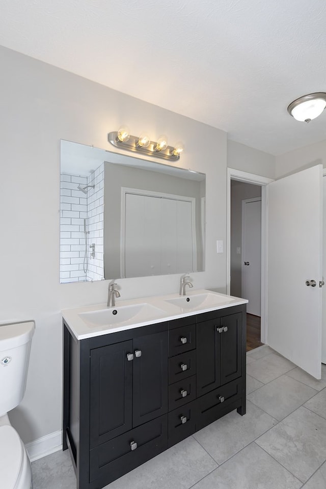 bathroom with tile patterned floors, a sink, toilet, and double vanity