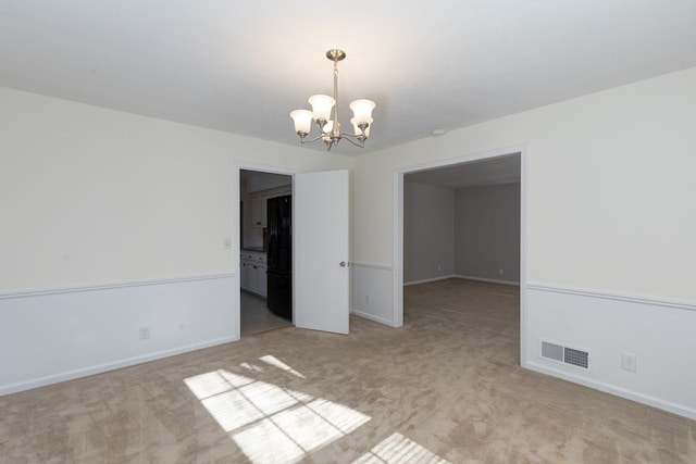 empty room with baseboards, visible vents, a chandelier, and light colored carpet