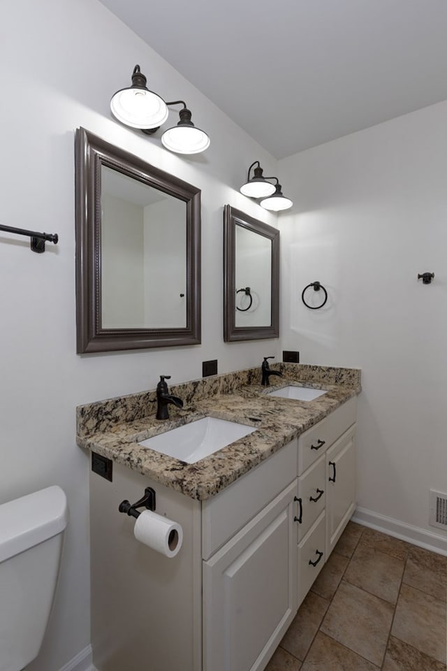 half bath with a sink, toilet, and double vanity