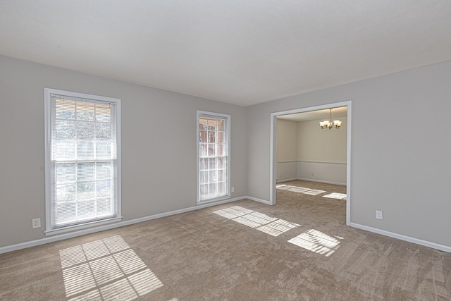 spare room with plenty of natural light, baseboards, and light colored carpet