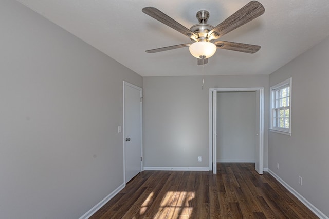 unfurnished room with dark wood-type flooring, baseboards, and a ceiling fan