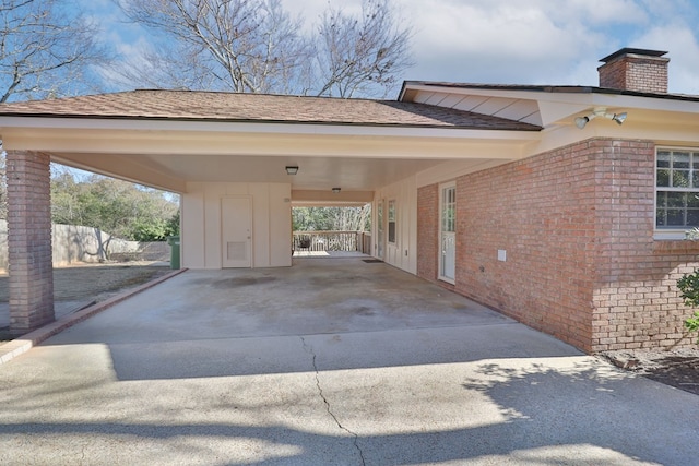 view of vehicle parking with an attached carport, concrete driveway, and fence