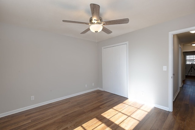 spare room with a ceiling fan, dark wood finished floors, and baseboards