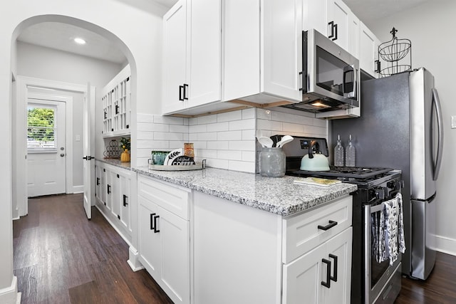 2901 Peabody Ave, Columbus, GA 31904 - kitchen with stainless steel appliances, dark wood-style flooring, arched walkways, and tasteful backsplash