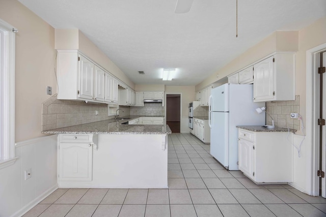 kitchen with decorative backsplash, white cabinetry, white appliances, and kitchen peninsula