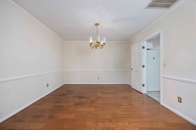 spare room with hardwood / wood-style floors, crown molding, and a chandelier