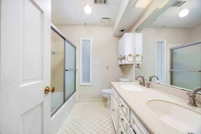 full bathroom featuring vanity, toilet, and bath / shower combo with glass door